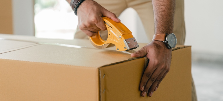 a man sealing cardboard box with ductape